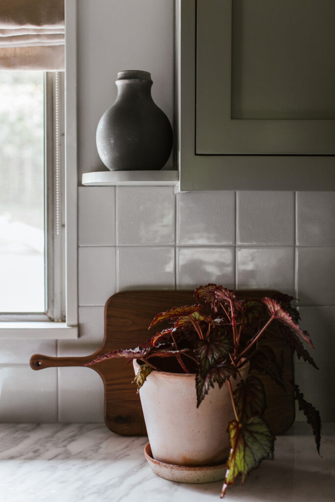 Kitchen counter detail of pottery, begonias and the backsplash