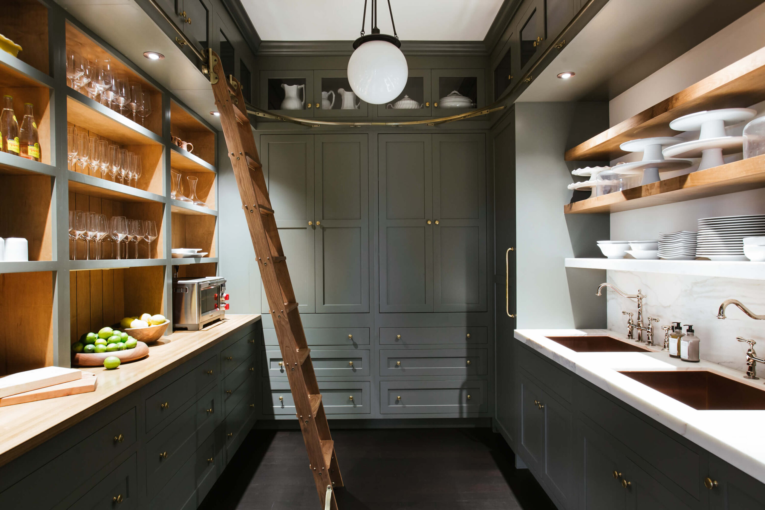 Luxury butler pantry with dark gray cabinets, marble counters and dual sinks