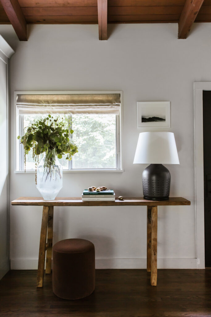 antique elm console table with lamp, books and vase of green foliage